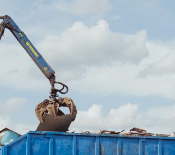 Crane-loading scrap grabber old metal at industrial metal recycling plant. Industrial metal waste recycling