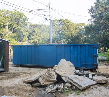 Removal of debris construction waste building demolition with rock and concrete rubble on portable bio toilet cabins at the construction site